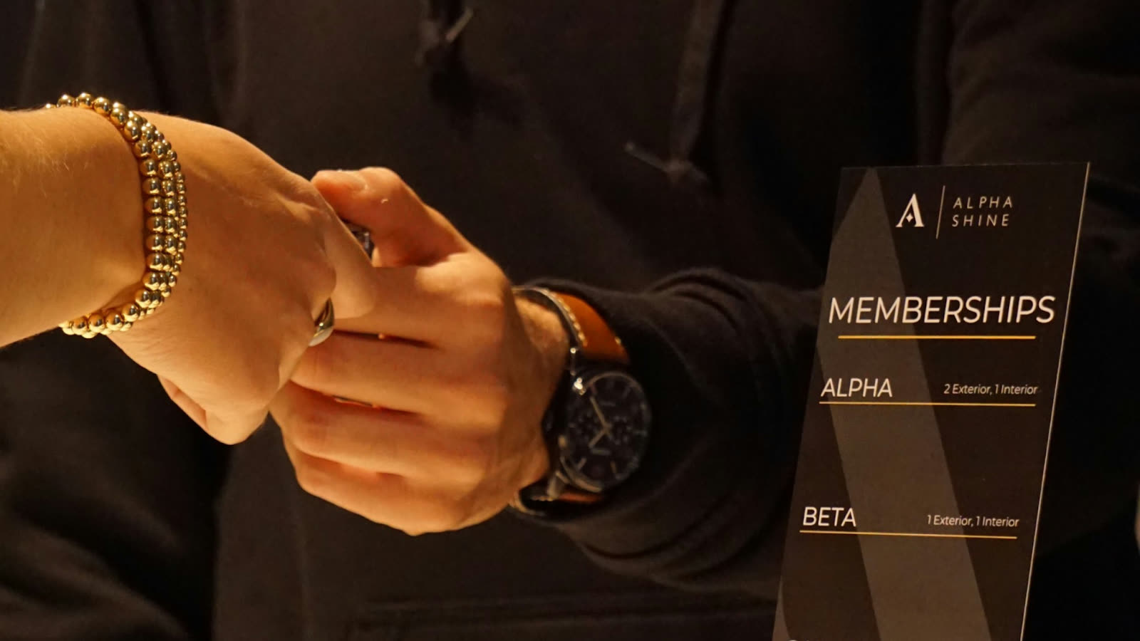 Customer handshake at ALPHASHINE valet service desk with membership card displayed, representing a seamless valet car detailing experience designed for busy lifestyles.