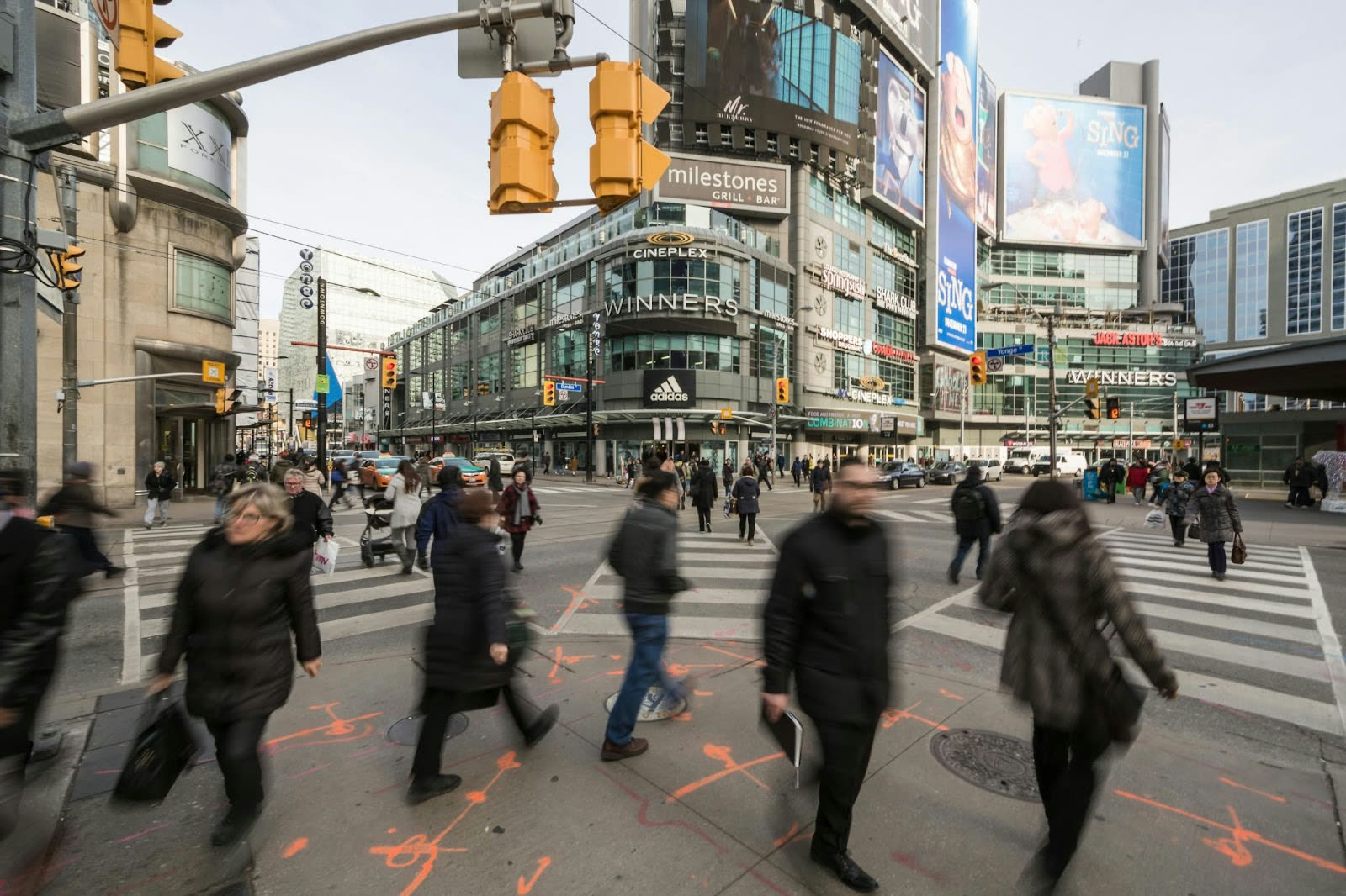 Busy street scene at Yonge-Dundas Square in downtown Toronto with pedestrians, shops, and bright billboards.