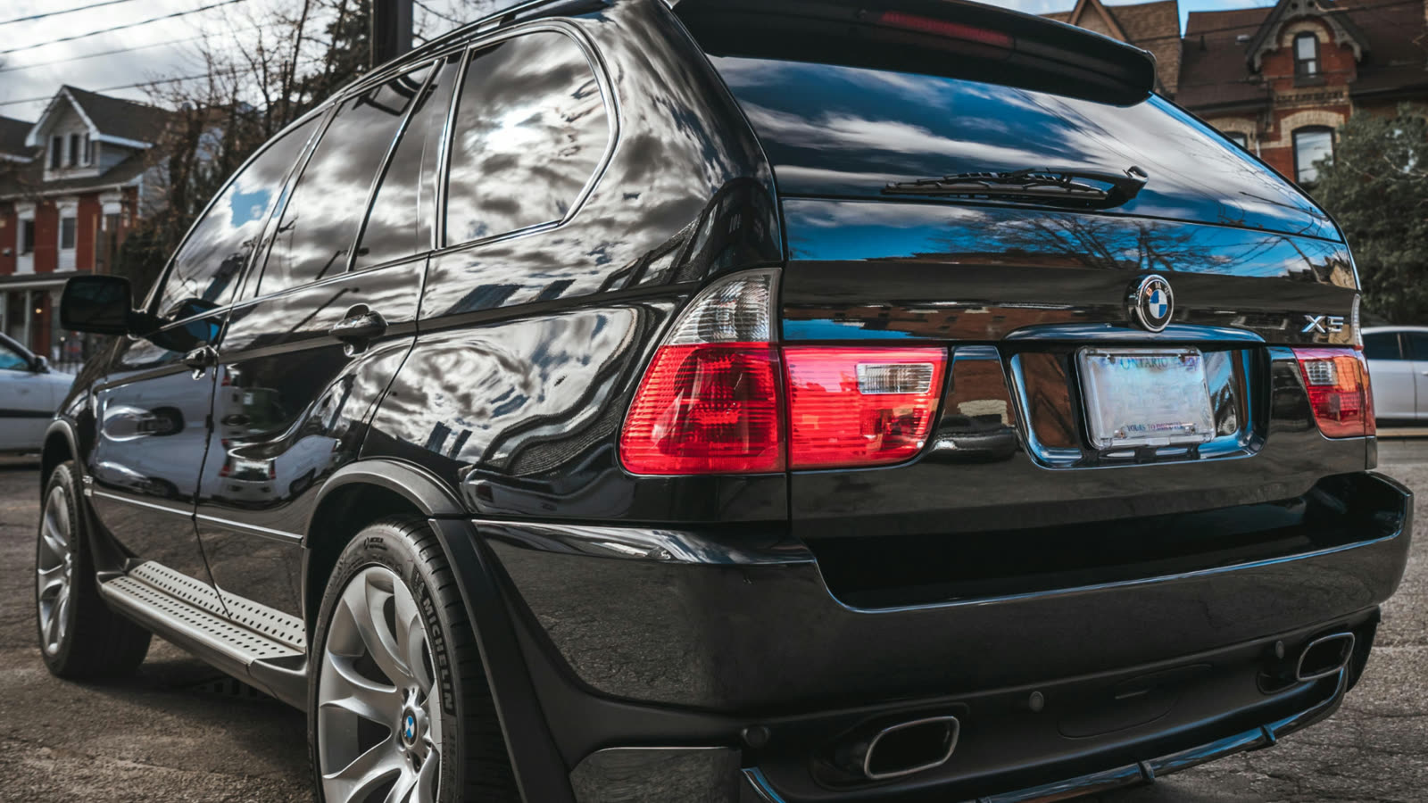 Clean black BMW SUV exterior after professional car detailing, showing glossy paint finish and clear reflections on the rear and side panels.
