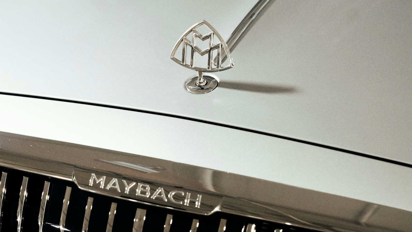 Close up of a Maybach hood ornament and front grille, showcasing chrome detailing on a luxury vehicle.