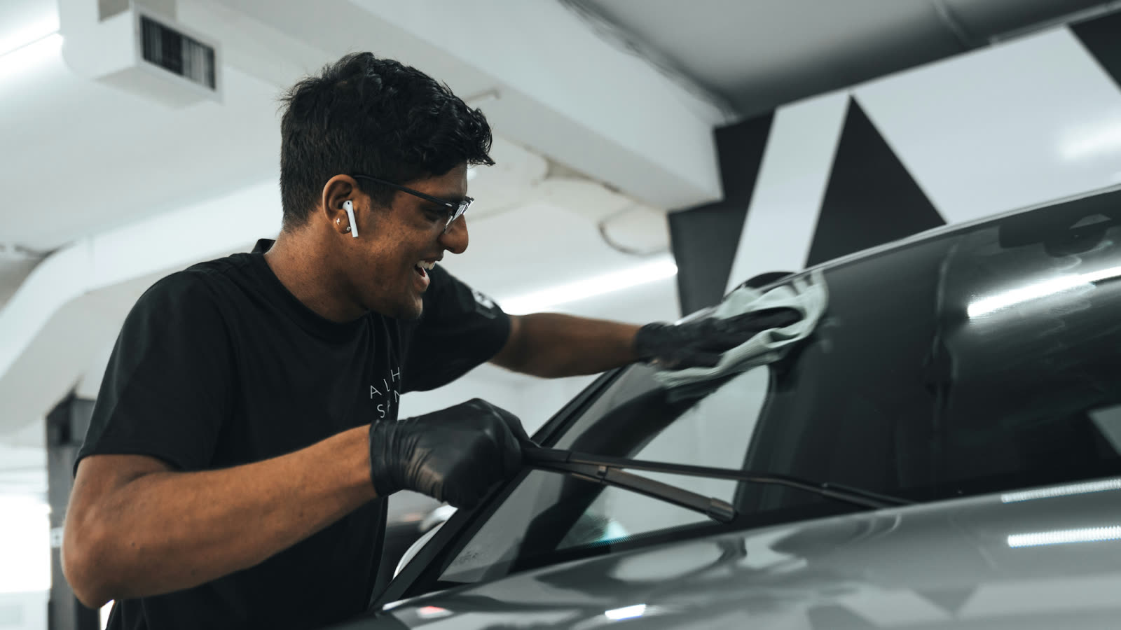 ALPHASHINE detailer carefully cleaning a car windshield during professional car detailing Toronto service, ensuring a spotless finish and clear visibility.