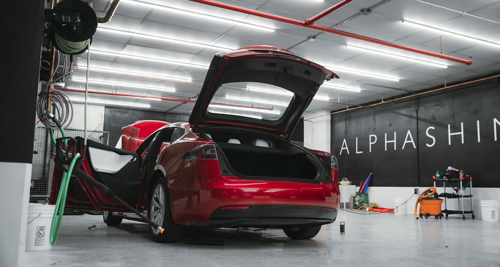 Red tesla parked in a car detailing facility being detailed on the interior
